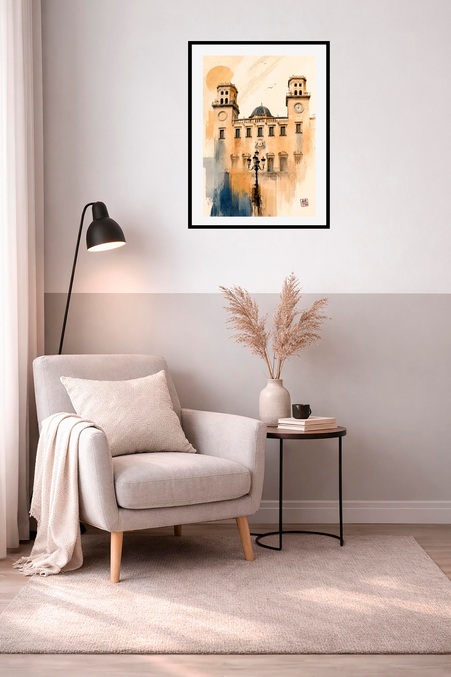 Cuadro enmarcado Ayuntamiento de Alicante en rincón de lectura con sillón gris claro, manta beige, lámpara de pie negra encendida y mesa auxiliar con jarrón de pampas y libros, acuarela vertical de fachada neoclásica en tonos ocre dorado IMAJIN-ARTE
