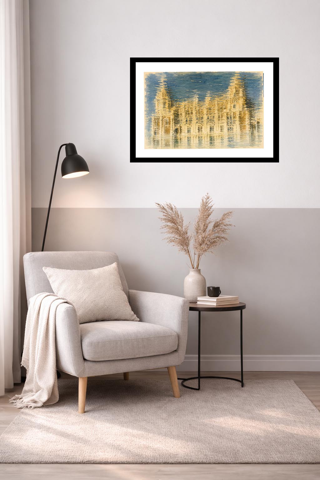 Lámina decorativa Solo Reflejo enmarcada en negro sobre sillón gris claro con manta, lámpara de pie negra y mesa auxiliar con jarrón de pampas y libros, rincón nórdico acogedor